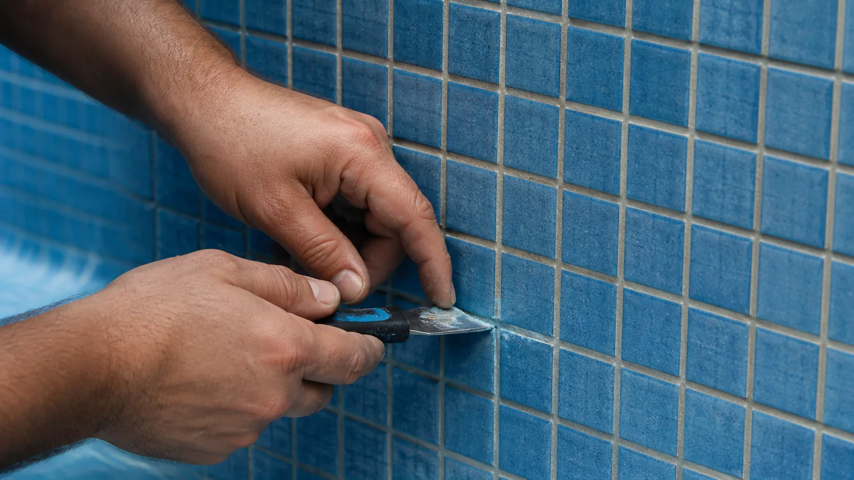 Reparo no revestimento de pastilhas azuis de uma piscina