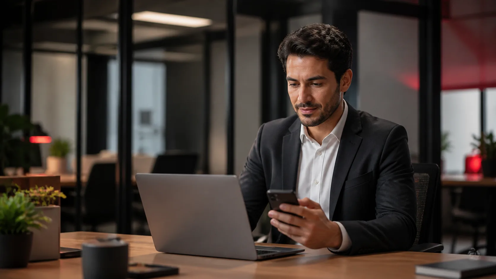 Profissional utilizando notebook e smartphone em escritório